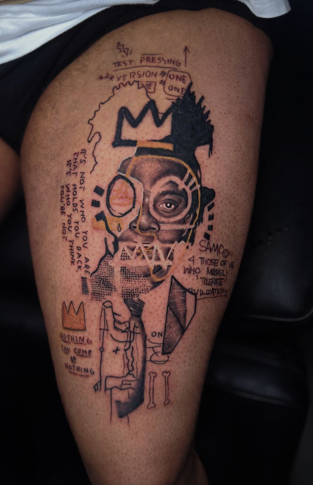 Collage-style thigh piece with crowns and text